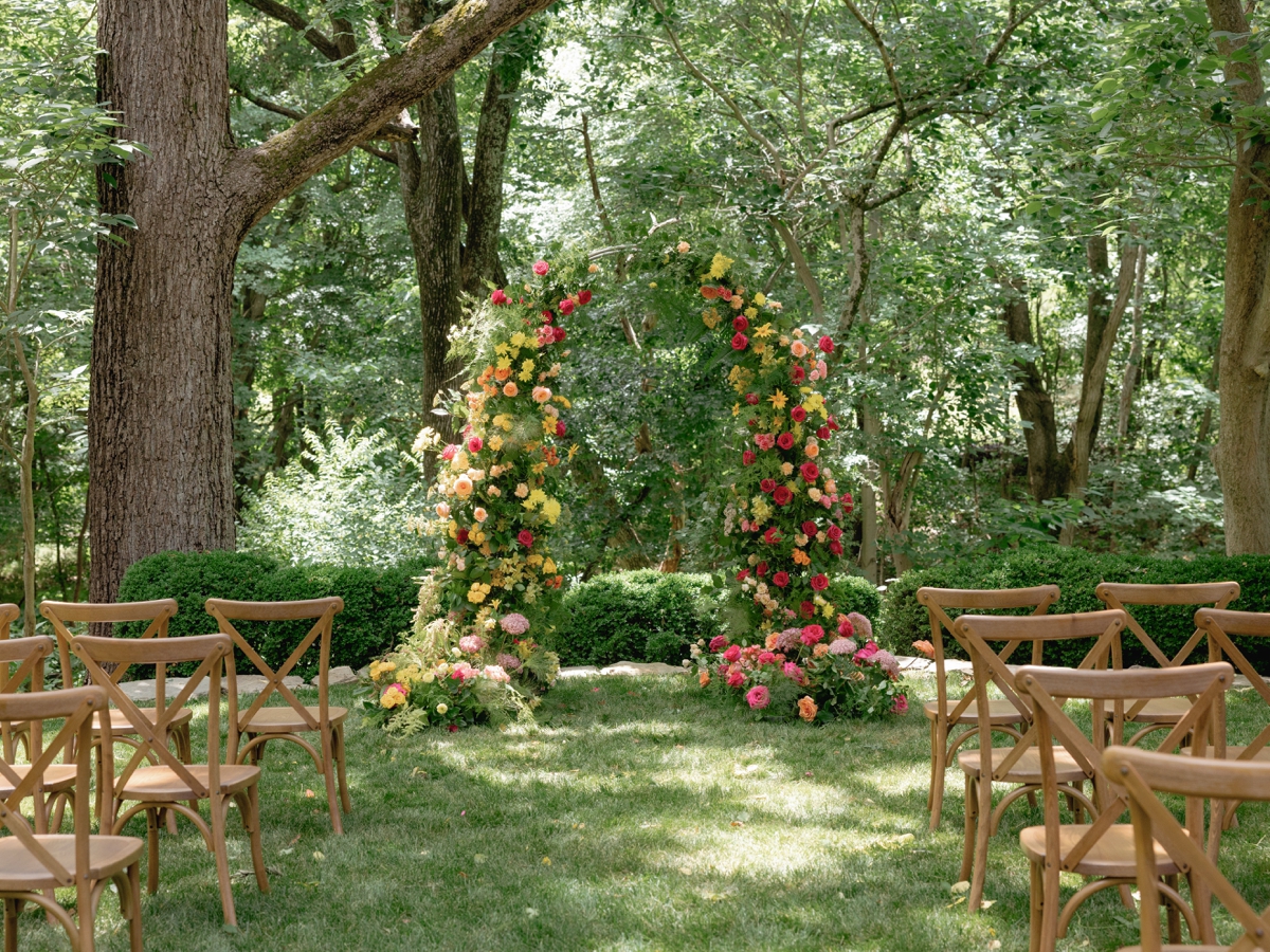 Orange, pink, and yellow wedding flower arch by Arrow Bella Weddings