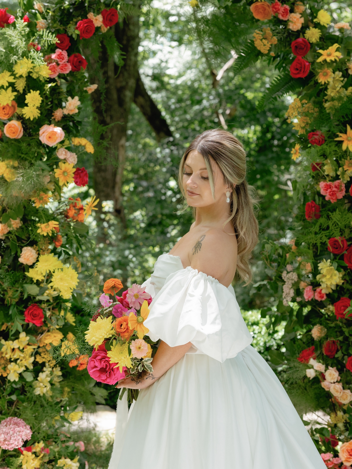 Bride holding a hot pink, orange, and yellow summer wedding bouquet filled with peonies, ranunculus, and roses