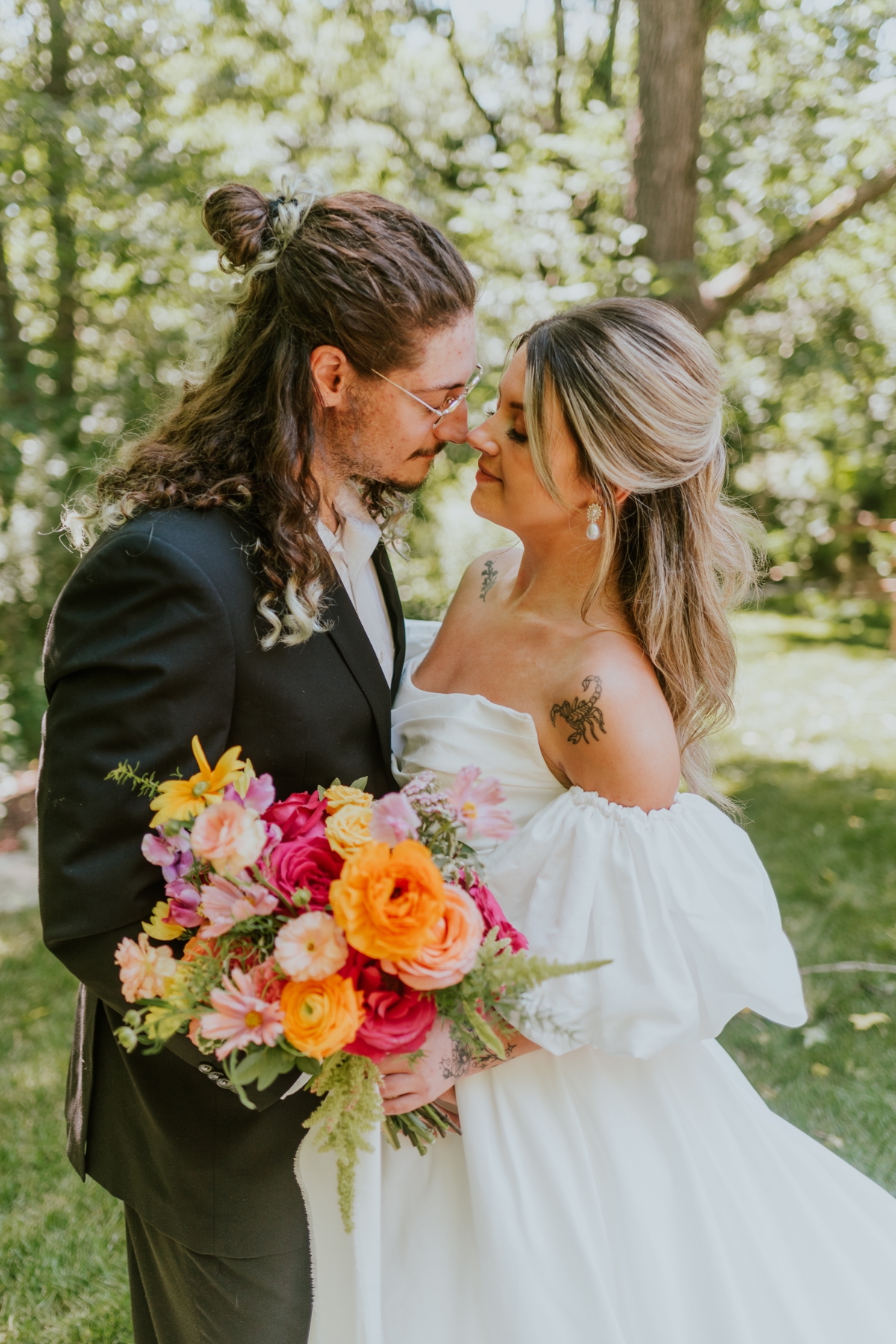 Bride holding a hot pink, orange, and yellow summer wedding bouquet filled with peonies, ranunculus, and roses