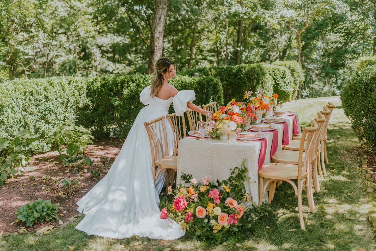 Bride standing next to an outdoor table for a citrus soiree-inspired styled wedding shoot