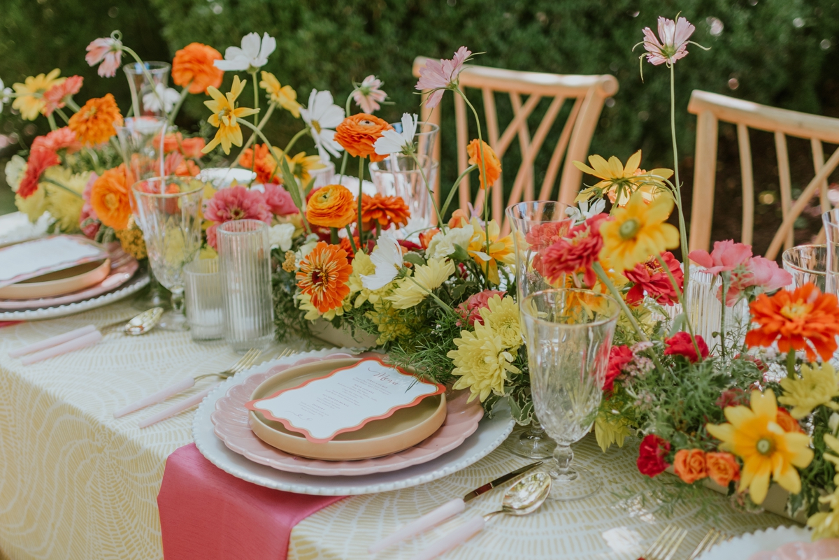 Orange, pink, and yellow floral table runner centerpiece for a citrus soiree-inspired styled wedding shoot