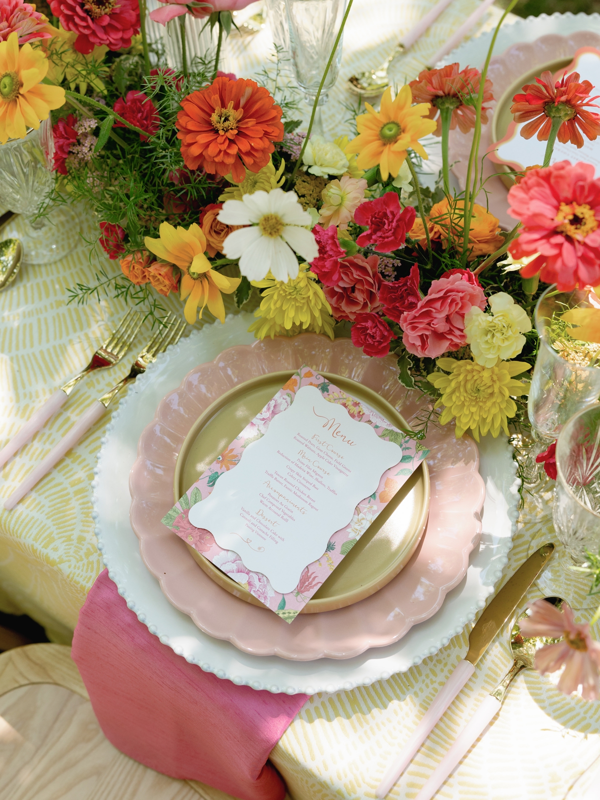 Wedding menu card with pink typography and colorful flower illustrations on a scalloped pink charger plate