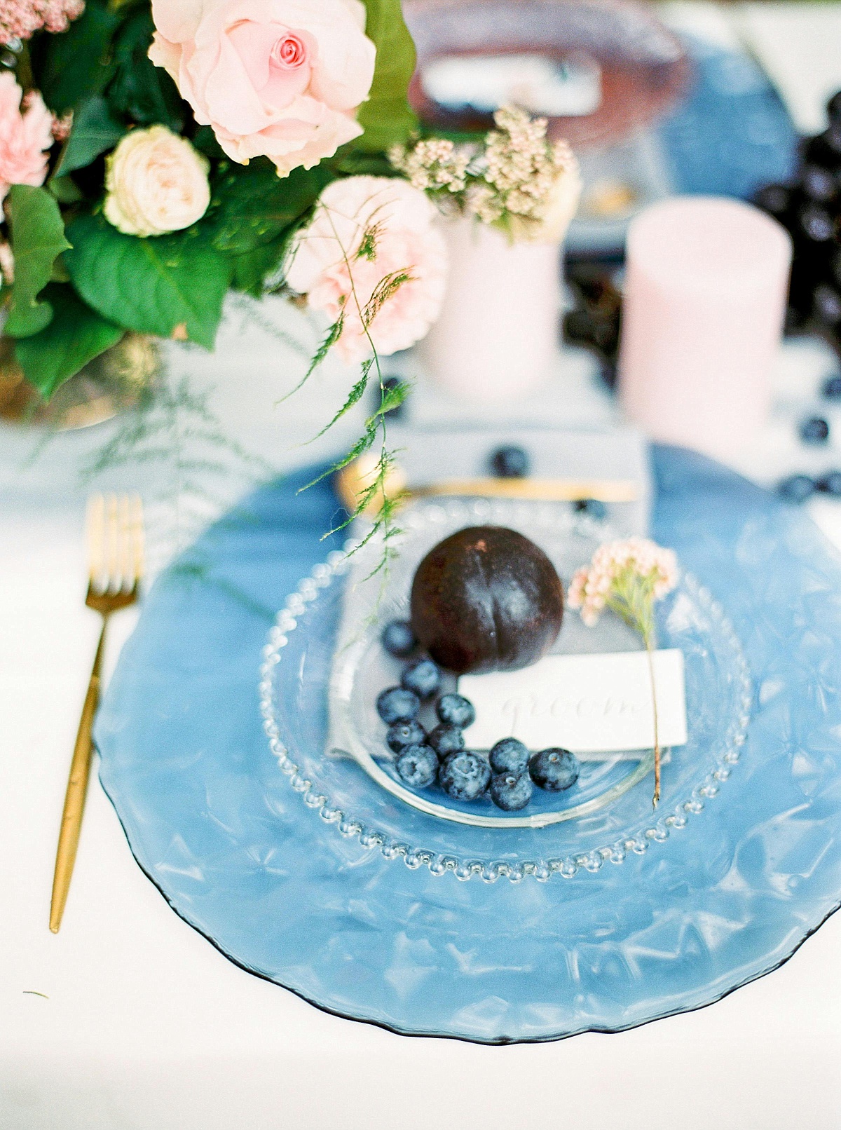 A plum and blueberries on a blue glass plate on a wedding table