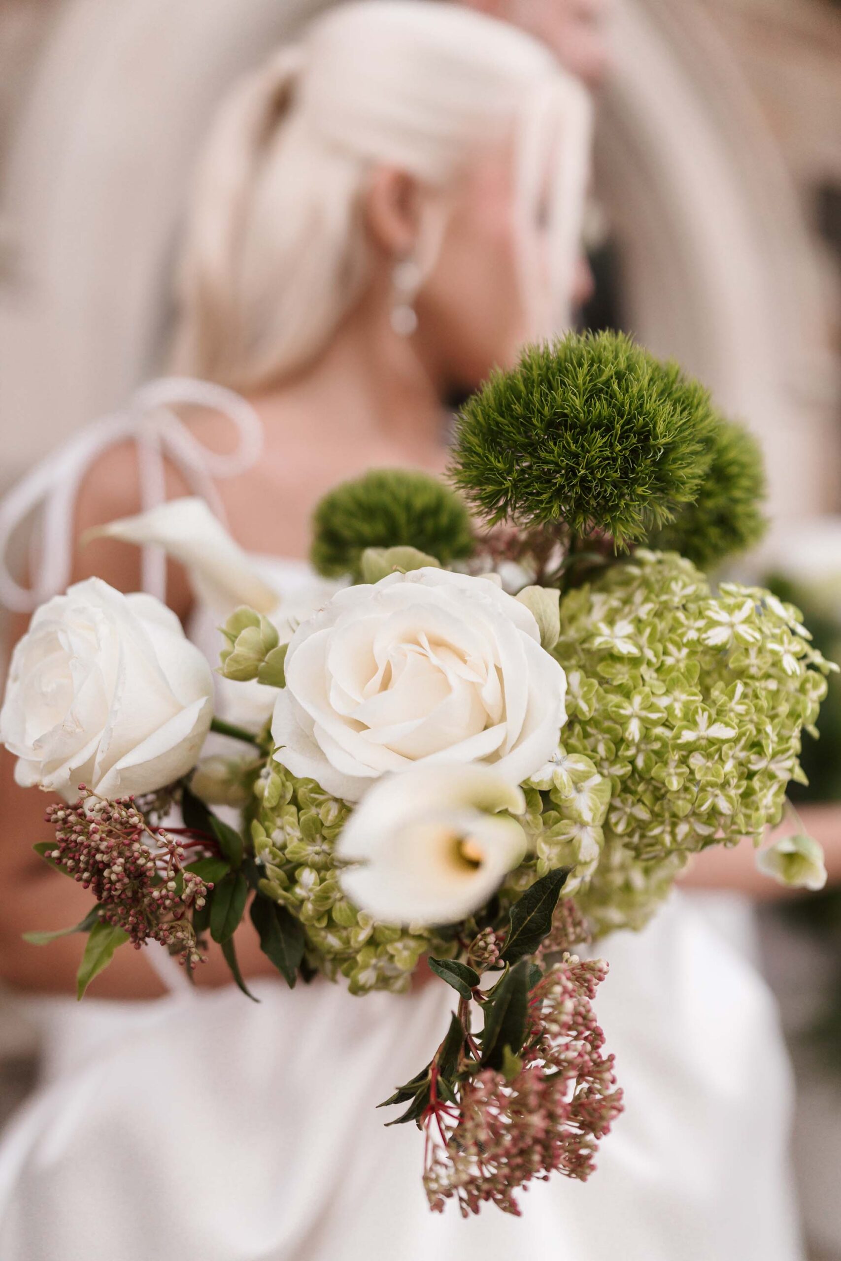Bride and groom embracing outside Cloisters Castle, with a trailing white gown and green-and-white bridal bouquet adding a natural garden romance feel.