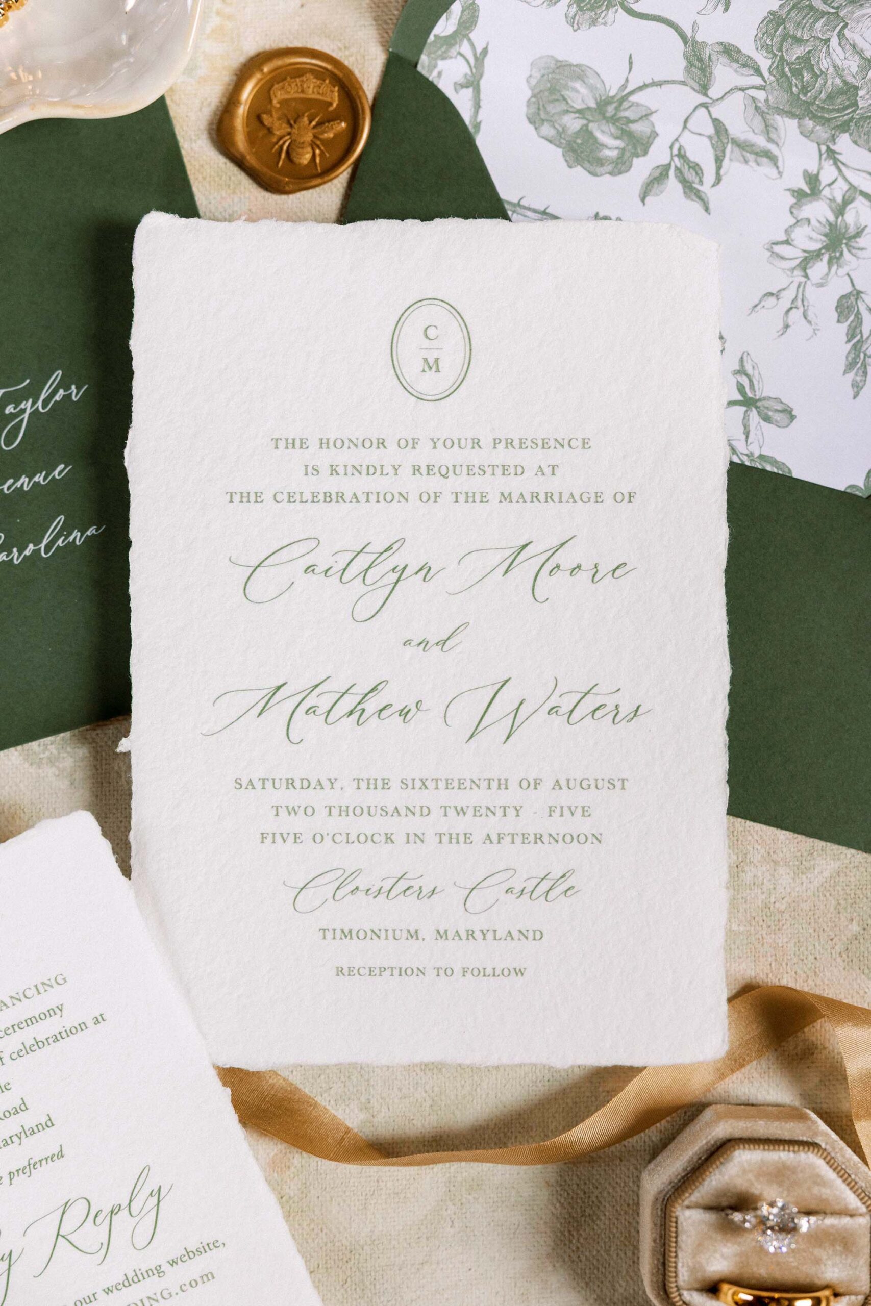Closeup of handmade wedding invitation suite with floral envelope liner and green calligraphy at Cloisters Castle in Timonium, Maryland