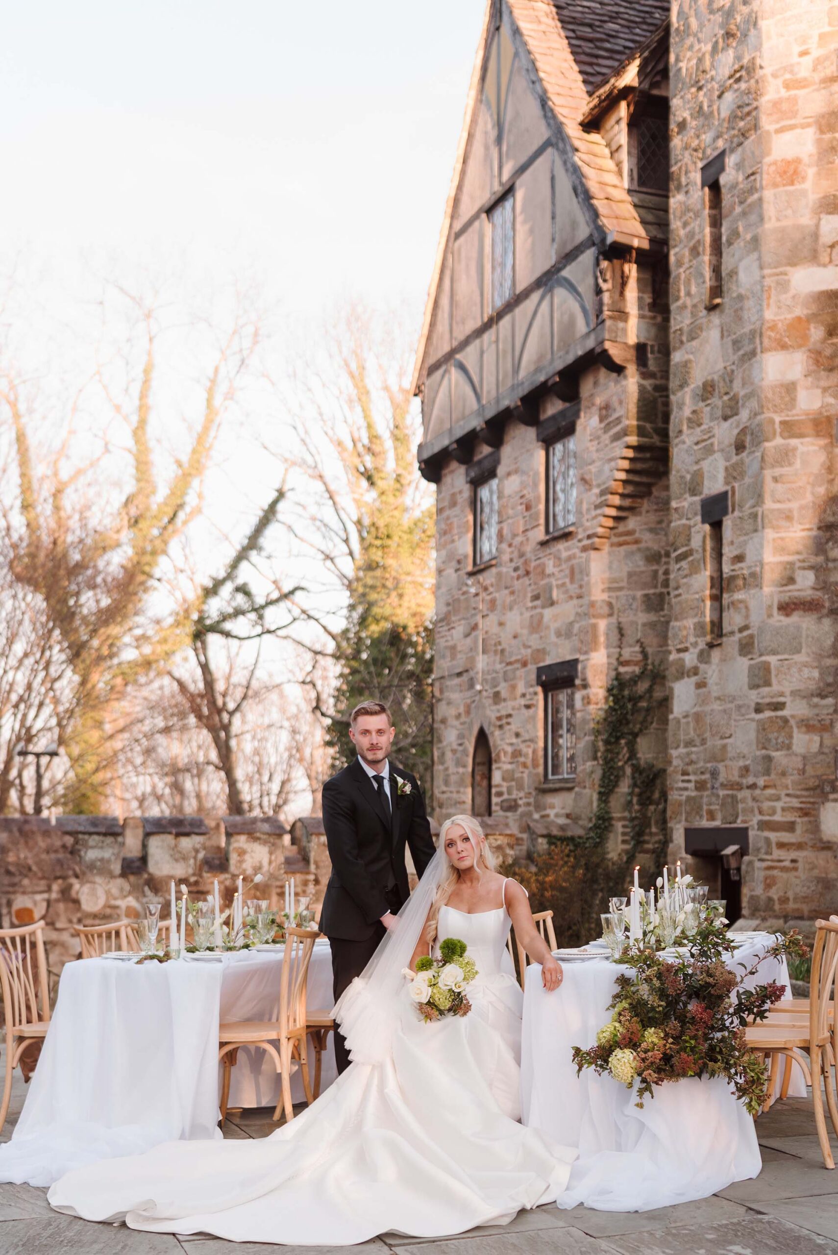 Bride and groom sitting beside a lush floral tablescape at their outdoor castle wedding reception