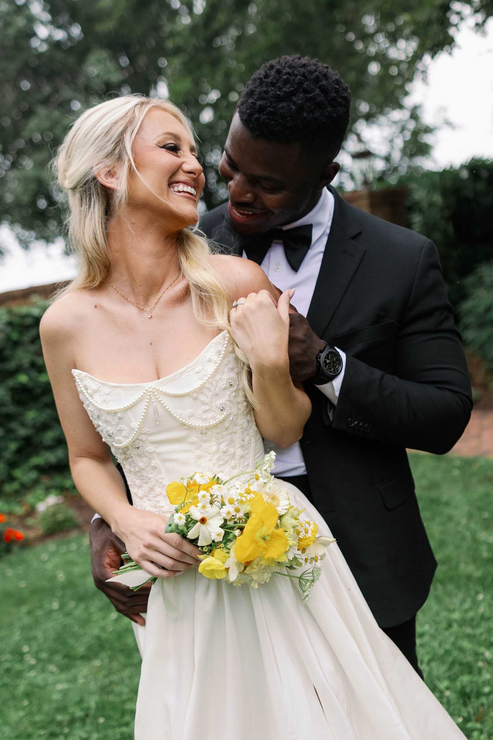 Bride and groom share a joyful moment at Brittland Estates, holding a yellow and white bouquet with wildflower charm.