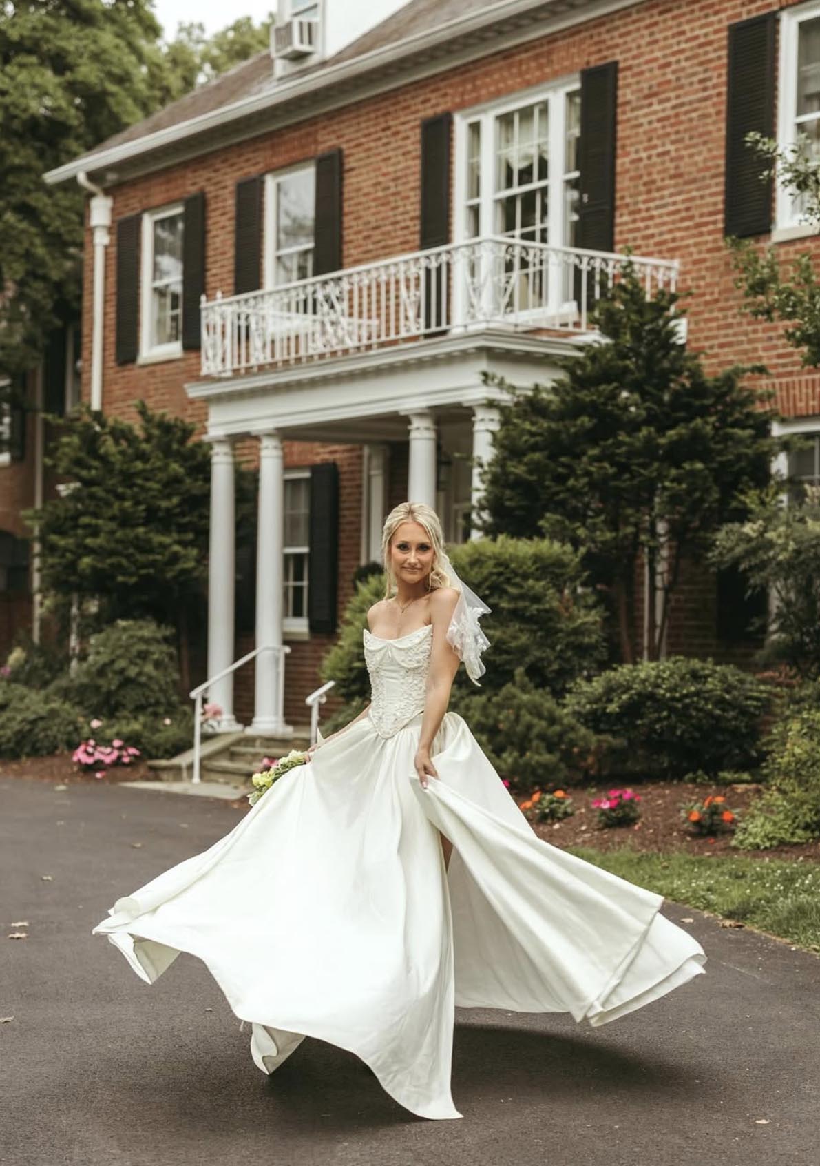 Bride twirls in elegant wedding gown in front of Brittland Manor’s brick façade during summer wedding in Chestertown, Maryland.