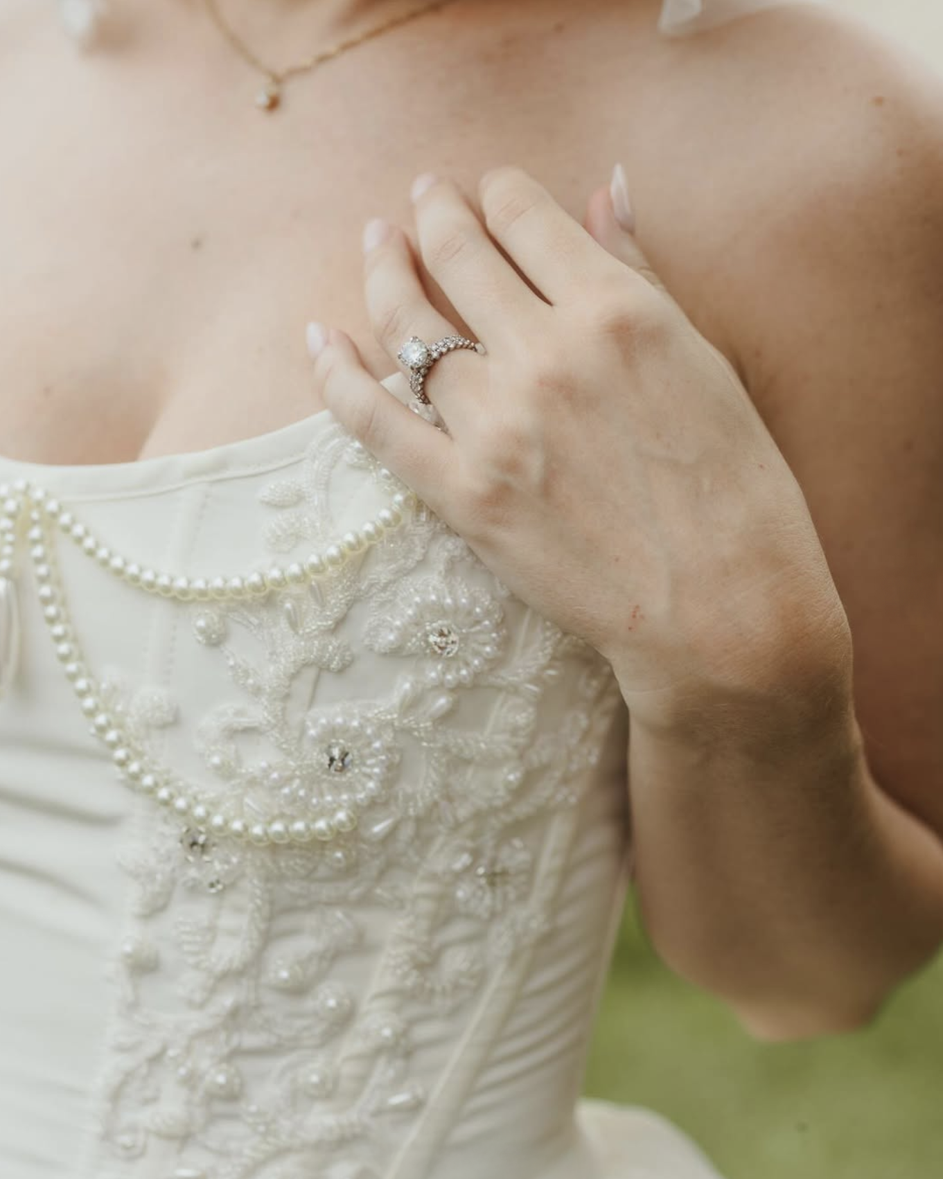 Close-up of beaded wedding dress bodice with pearl detailing and bride’s hand showing diamond engagement ring at Brittland Estates wedding.