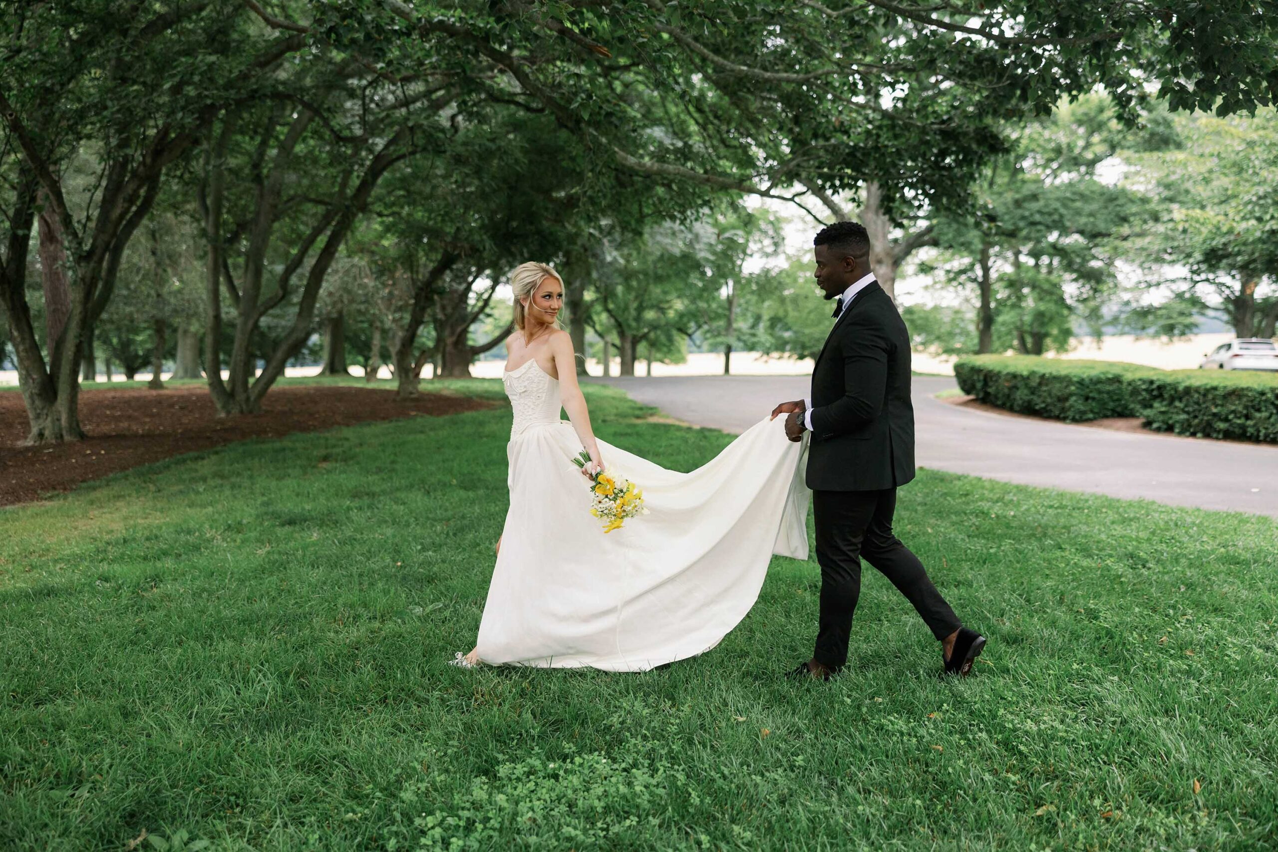 Bride and groom walking across the lawn at Brittland Estates with soft summer florals and a romantic garden wedding aesthetic.