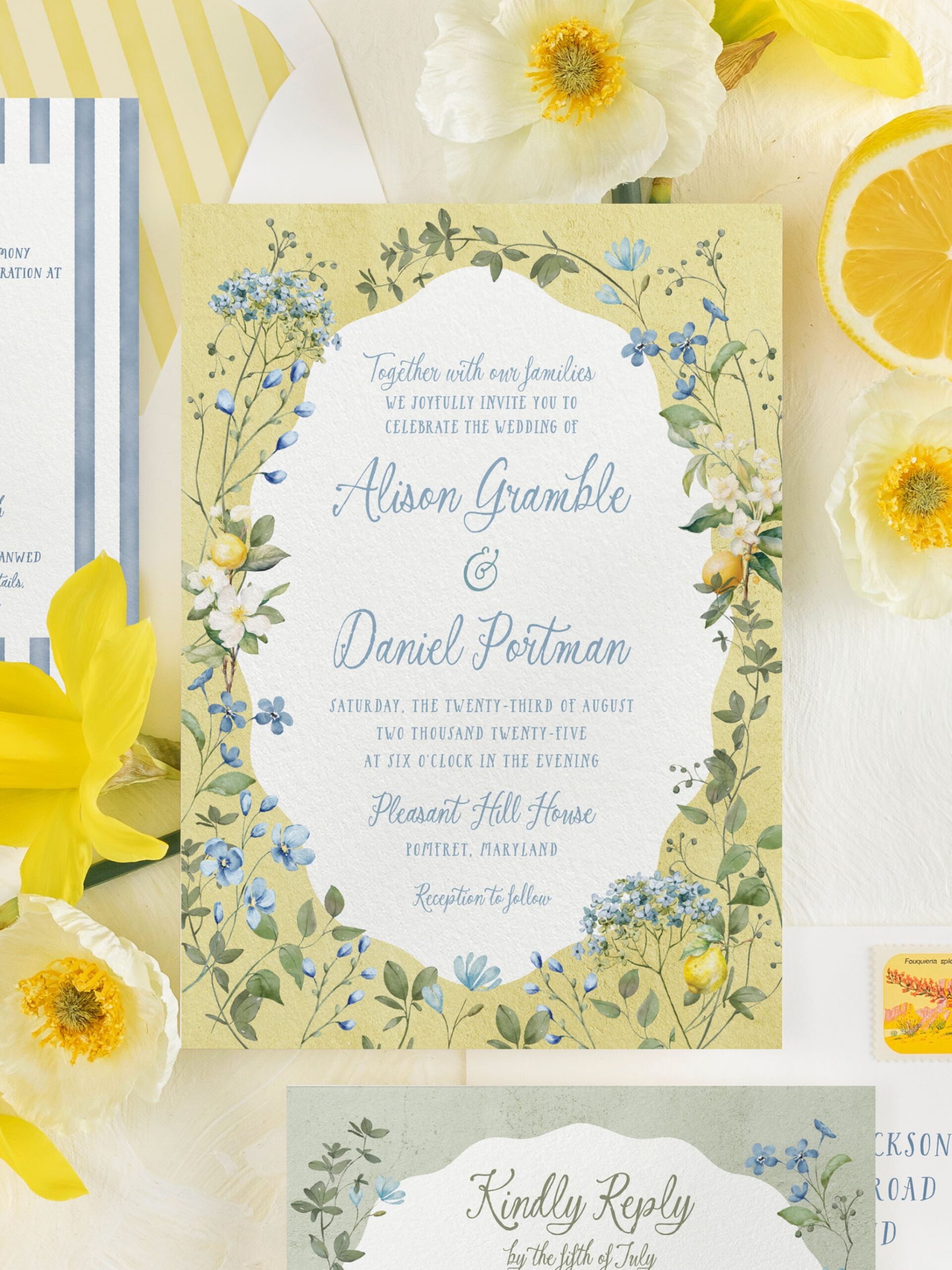 Close-up flatlay of lemon and blue wildflower wedding invitation featuring botanical border, elegant calligraphy, and yellow daffodil and lemon accents.