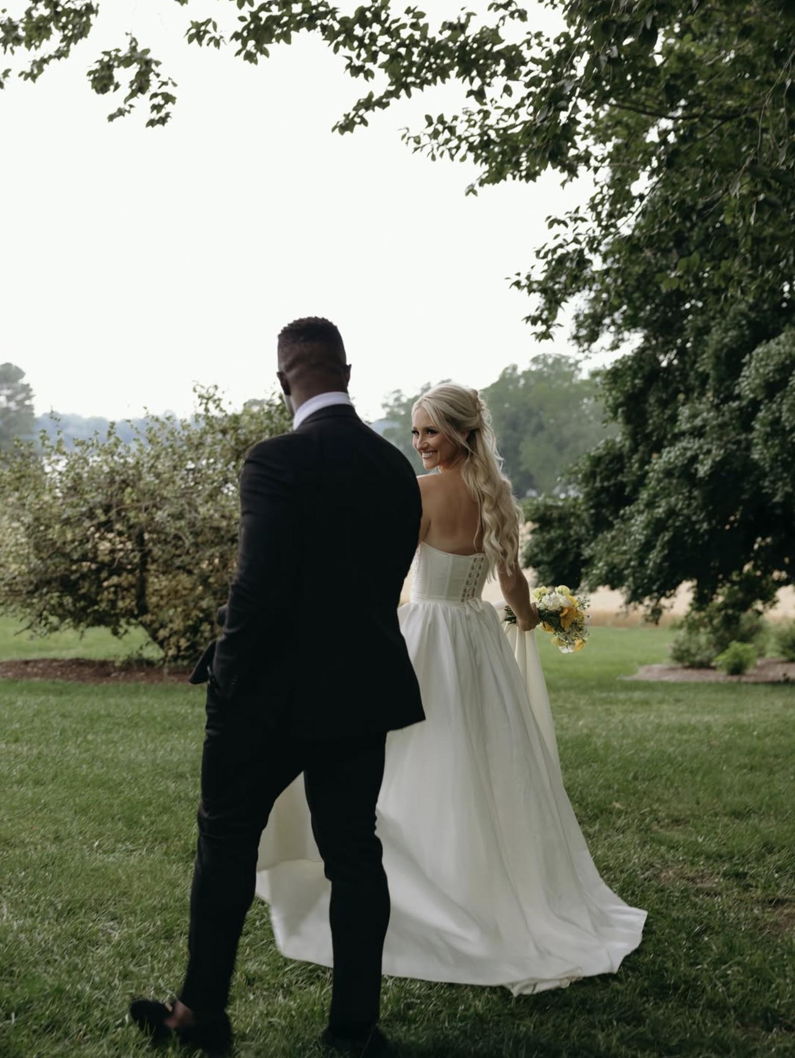 Bride and groom walking hand-in-hand on lush green grounds at Brittland Estates during romantic Eastern Shore wedding.