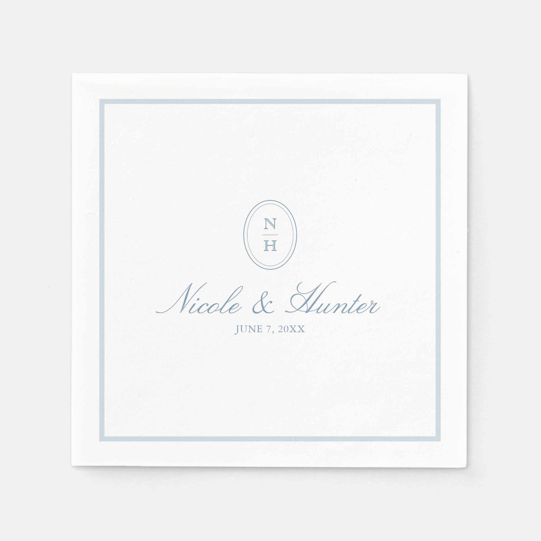 White wedding napkin with dusty blue border, oval monogram initials, couple’s names and wedding date in elegant script.