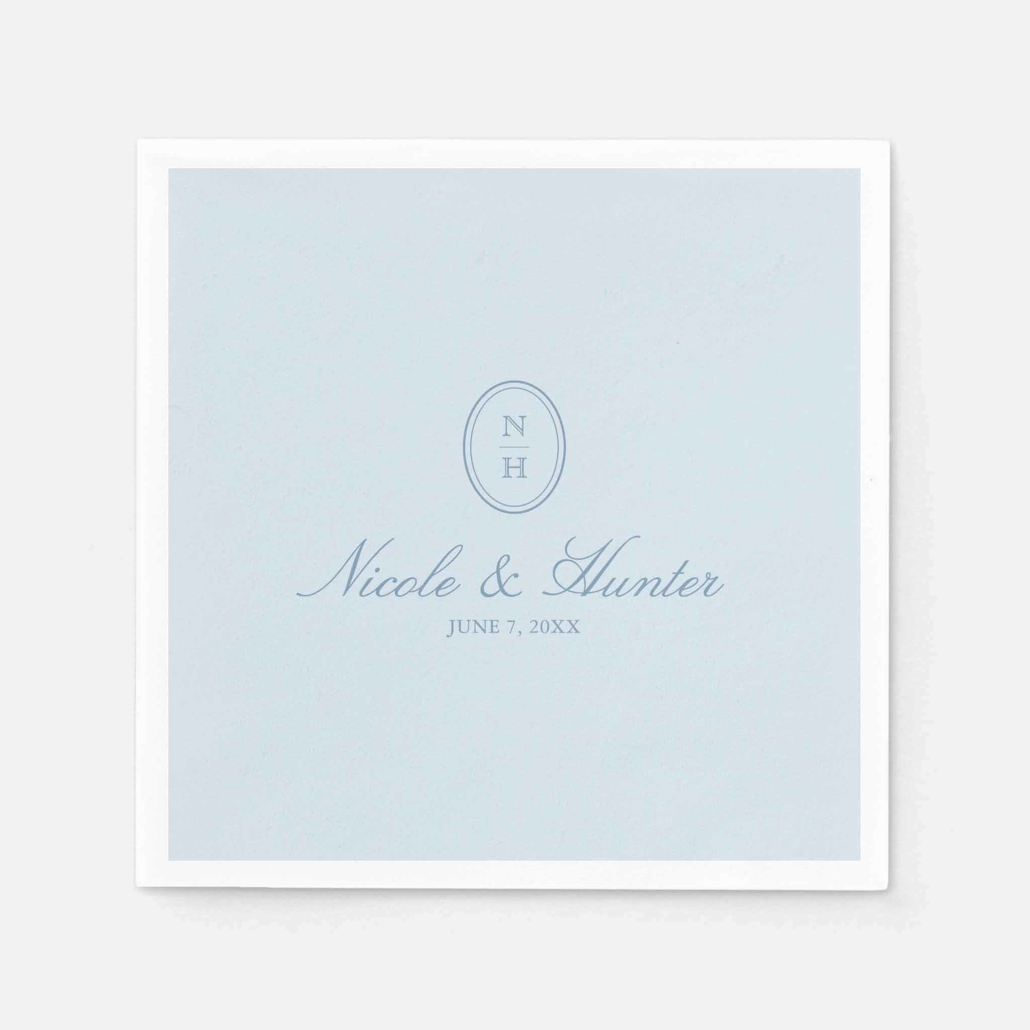 Dusty blue wedding napkin with oval monogram initials, couple’s names and wedding date printed in soft blue script.